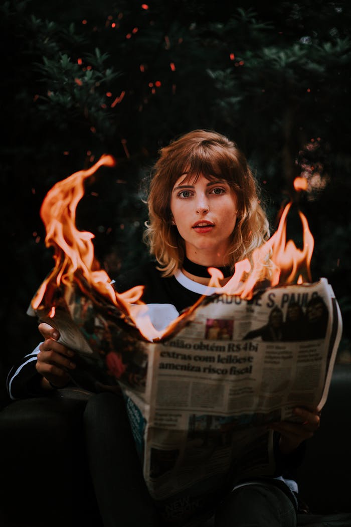 services-02 A young woman holding a burning newspaper, creating a dramatic scene.